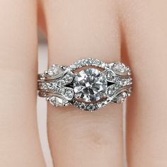 a woman's hand with a diamond ring on top of her wedding band and an engagement ring in the middle