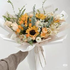 a bouquet of sunflowers and other flowers is wrapped in white paper