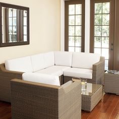 a living room with wicker furniture and large windows in the back ground, along with wooden flooring