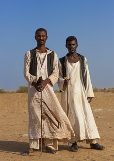 two men standing in the desert with their backs turned to look like they are holding canes