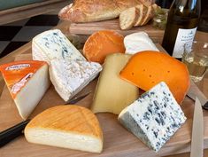 a wooden cutting board topped with different types of cheese