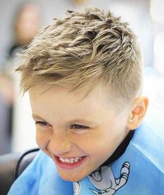 a young boy with blonde hair smiling at the camera