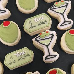 decorated cookies with green and white frosting on a black surface, including cocktails