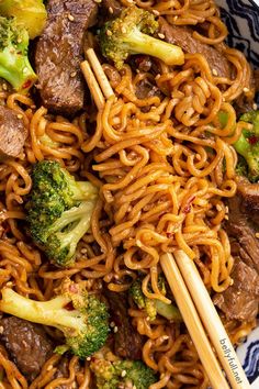 beef and broccoli stir fry with chopsticks in a blue and white bowl