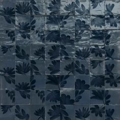 an artistic tile design with leaves and flowers painted on the side of it in dark blue tones