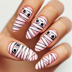 Add a cute twist to your Halloween manicure with this playful pink mummy nail design! These almond-shaped nails feature a soft pink base wrapped in black and white stripes, resembling mummy bandages, with adorable googly eyes peeking through. Perfect for those who want to keep their Halloween look fun and lighthearted, this manicure blends spooky with sweet in a delightful way. Get ready to impress with these charming mummy nails! #HalloweenNails #MummyNails #CuteNailArt #SpookySeason #PinkNails #HalloweenManicure #FunNails Googly Eye Nails, Halloween Gender Reveal Nails, Mummy Nails Halloween, Halloween Nails Mummy, Halloween Mummy Nails, Mummy Nail Art, Halloween Fingernails, Mummy Bandages, Mummy Nails