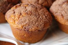 muffins with powdered sugar on top sitting on a white plate next to other muffins