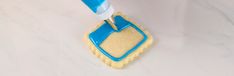 a cookie being decorated with icing and a blue spatula on top of it