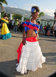 a woman in a colorful dress is standing on the street with other people around her