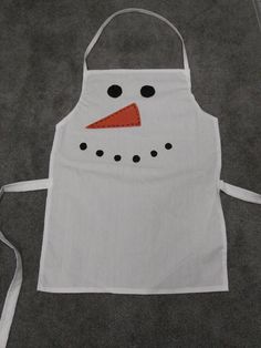 a white apron with a snowman design on the front and an orange nose sticking out of it