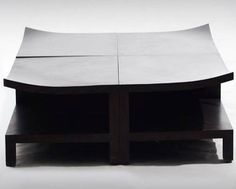 an unusual coffee table made out of two pieces of plywood and black wood, with one section open to show the top