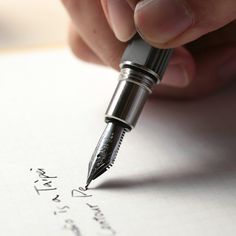 a person writing with a fountain pen on top of a piece of paper that says i love you