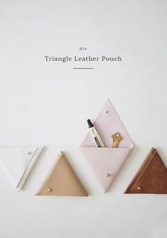 three triangle shaped leather pouches sitting next to each other on top of a white surface