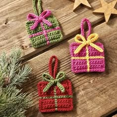 three crocheted christmas ornaments on a wooden table next to pine branches and a star