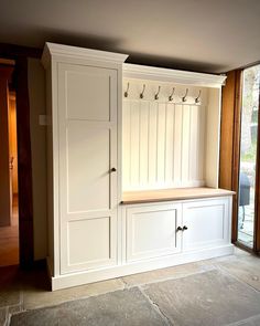 an empty room with white cabinets and hooks on the doors