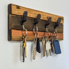 five keys hang on a wooden key holder with six different styles of keys hanging from it