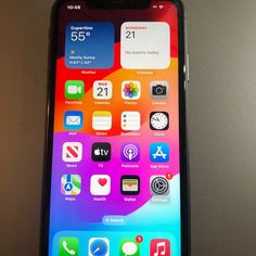 an iphone with the home screen showing icons on it's back side, sitting on top of a table