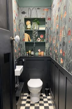 a bathroom with a toilet, sink and bookcase in it's wallpaper