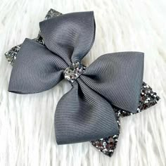 a gray bow with silver sequins on it sitting on a white fur surface