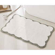 a bathroom rug with a white and green border on the floor next to a bathtub