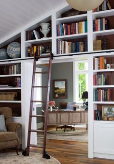 a living room filled with lots of books on top of white shelving unit units