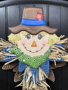 a scarecrow door hanger with a hat on it's head and eyes