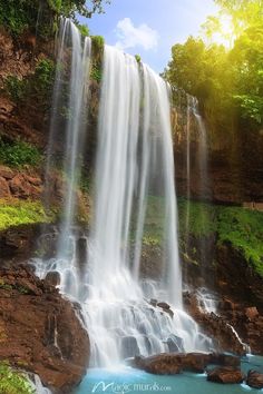 a large waterfall with blue water in the foreground