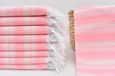 pink and white towels stacked on top of each other next to a basket with a woven handle