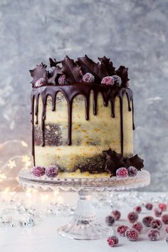 a cake with chocolate frosting and raspberries sitting on top of a glass plate