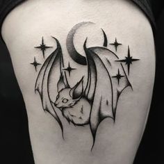 a bat tattoo on the back of a woman's thigh, with stars around it