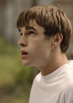 a close up of a person wearing a white t - shirt and earrings