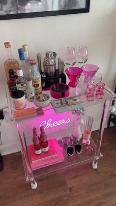 a pink bar cart with bottles and glasses on it