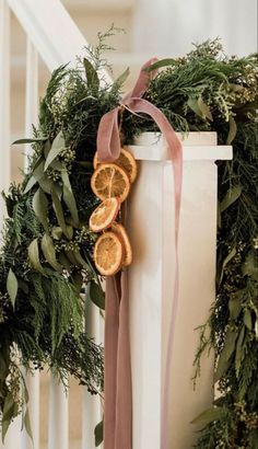 an orange slice is tied to the side of a white railing with greenery around it