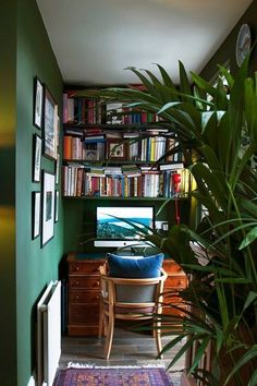 a room with green walls and lots of books on the shelves next to a desk