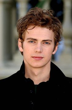 a close up of a person wearing a black shirt and looking at the camera with a serious look on his face