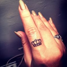 two fingers with tattoos on them, one has a crown