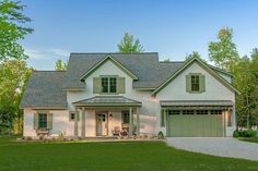 a large white house with green shutters on the front and two story garage doors