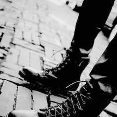 black and white photograph of man's legs with shoes on brick walkway in urban setting