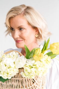 a woman holding a basket with flowers in it