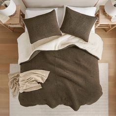 an overhead view of a bed with two pillows and blankets on top of the bed