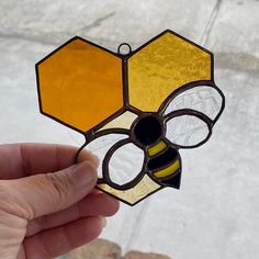 a hand holding a stained glass bee decoration