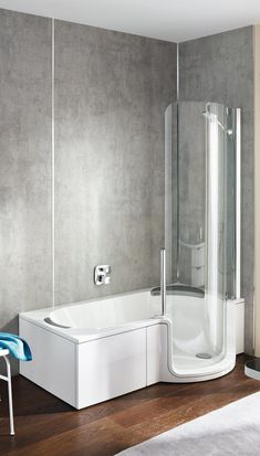 a white bath tub sitting on top of a wooden floor next to a shower stall