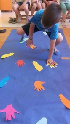 a little boy playing with paper cutouts on the floor