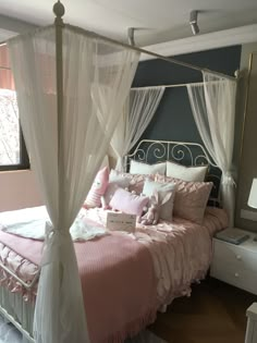 a white canopy bed with pink and white pillows