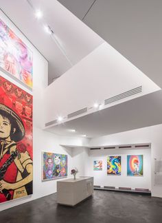 an art gallery with paintings on the wall and ceiling lights hanging from the rafters