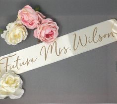 some flowers and a ribbon with the word future mrs wilson on it in gold lettering