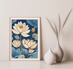 a white vase sitting on top of a table next to a framed art print with water lilies