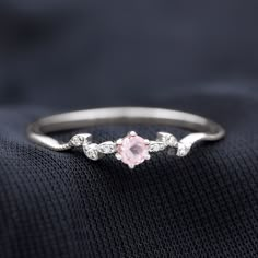 a pink diamond ring sitting on top of a black cloth