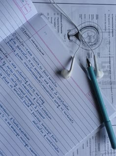 a pair of headphones sitting on top of a piece of paper next to a pen