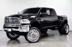 a black truck is parked in a large room with chrome rims and tires on it